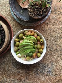 High angle view of fruits in bowl on table, vegan food, vegan salad, avocado, olives, plant, 