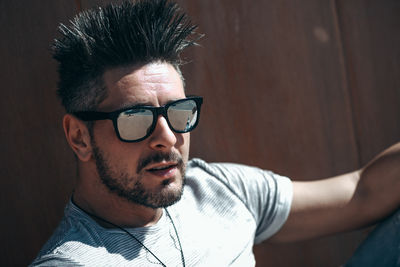 Close-up portrait of handsome man wearing sunglasses against wall