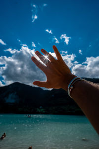 Midsection of person by sea against blue sky