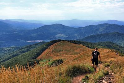 Rear view of man looking at mountains against sky