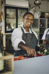 Portrait of smiling female colleague preparing food in truck