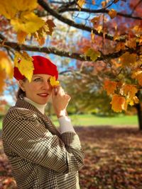 Portrait of young woman standing against tree