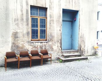 Empty chairs outside house against building