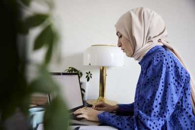 Businesswoman in headscarf working on laptop at home