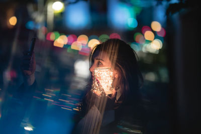 Beautiful woman taking selfie with glowing jar in city at night