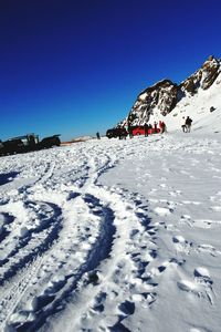 Snow covered landscape against clear blue sky