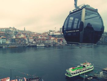 Boats moored in river by buildings in city against sky