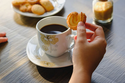 Midsection of person holding coffee cup on table