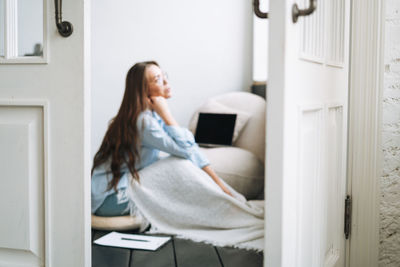 Portrait of young woman sitting on bed at home