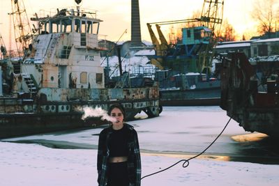 Woman exhaling smoke while standing at harbor