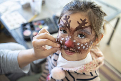 Cute girl with painted face at home during christmas