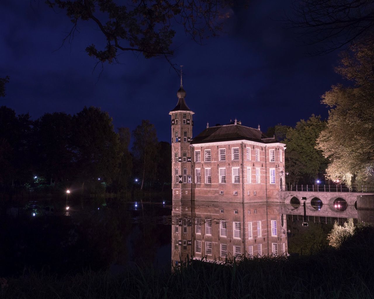 architecture, tree, building exterior, built structure, reflection, illuminated, night, water, sky, travel destinations, dark, history, outdoors, standing water, canal, castle, tourism, riverbank, medieval