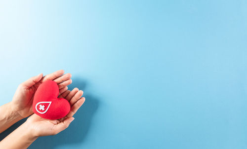 Close-up of hand holding heart shape over white background