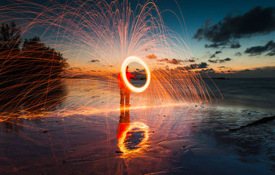 Light trails on beach against sky at night