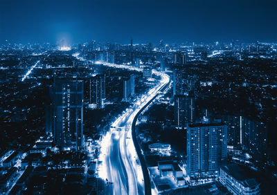 High angle view of illuminated street amidst buildings in city at night