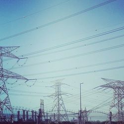 Low angle view of electricity pylon against blue sky