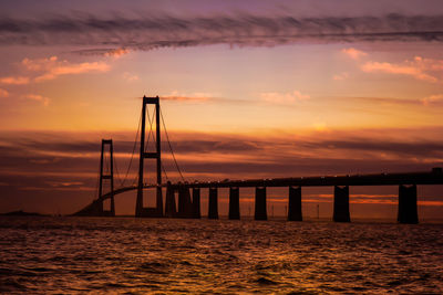 Suspension bridge over sea during sunset