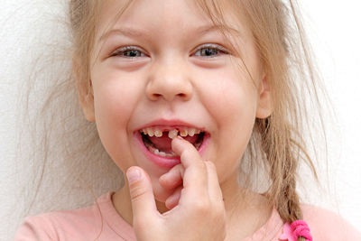 Happy and smiling caucasian little girl of 5  years touching loose tooth by finger looking at camera