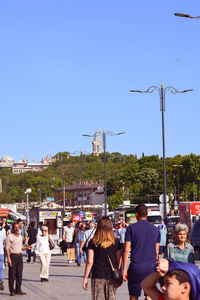 People on street against clear blue sky