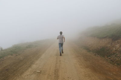 Rear view of man walking on road