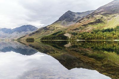 Reflection of rocky mountains in river against sky