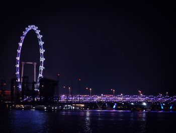 Illuminated singapore flyer against clear sky at night