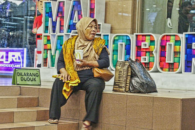 Full length of woman sitting outdoors