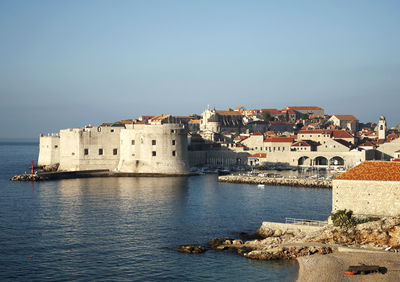 Buildings by sea against clear sky