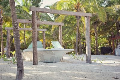 Old boat on tropical beach surrounded by palm trees