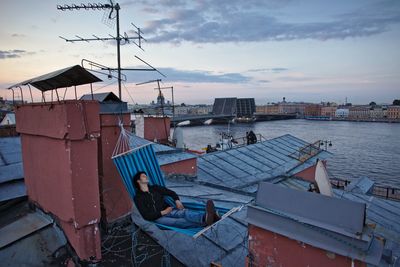 High angle view of teenager lying in hammock next to river