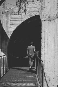 Rear view of man walking on building wall