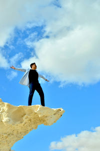 Low angle view of young woman standing against sky