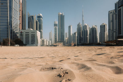 View of sand dunes of desert against backdrop of blurry skyscrapers. financial business part of city