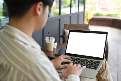 Midsection of man using mobile phone while sitting on table