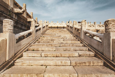 Low angle view of staircase against cloudy sky