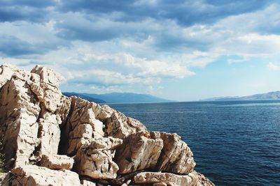 Rock formation by sea against sky