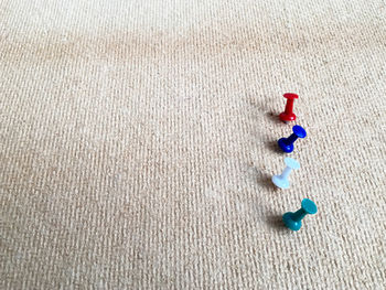 High angle view of colorful thumbtacks on burlap