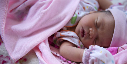 Baby girl sleep in bed, sleeping new born child on pink blanket.