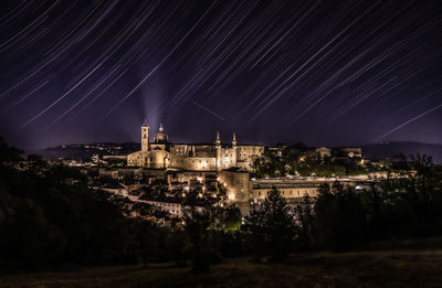 Illuminated buildings in city against sky at night