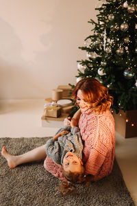 Happy mom and little daughter kid in sweaters hugging getting ready for  christmas holiday at home