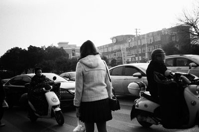 Rear view of people walking on street in city