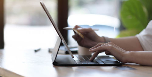 Midsection of woman using mobile phone on table