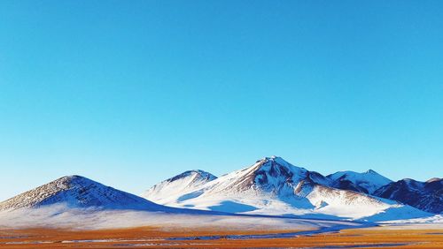 Scenic view of snowcapped mountains against clear blue sky