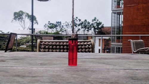 Red metallic structure by building in city against sky