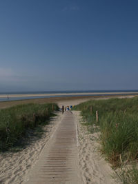 Footpath leading towards sea against sky