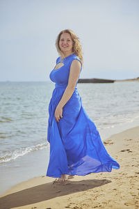 Portrait of smiling young woman standing at beach