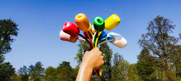 Low angle view of hand holding toy against sky