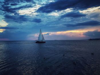 Sailboat sailing on sea against sky during sunset