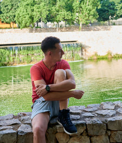 Side view of boy sitting on retaining wall