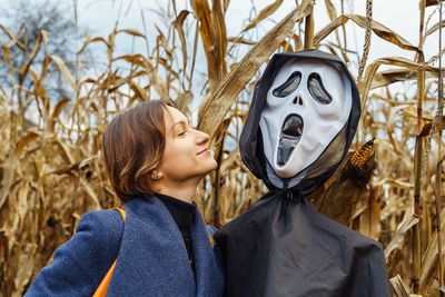 Woman looking at an effigy with a mask of death in a cornfield in halloween